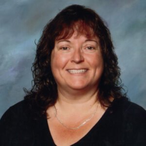 Smiling woman with wavy brown hair and black shirt.