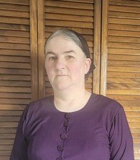 Woman in purple blouse near wooden shutters