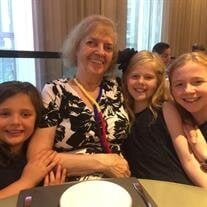 Elderly woman smiling with three young girls indoors.