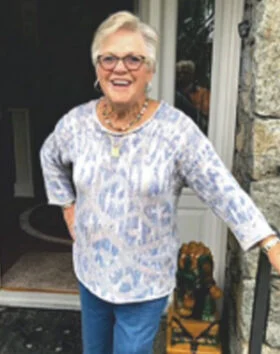 Smiling woman standing at door with stone wall