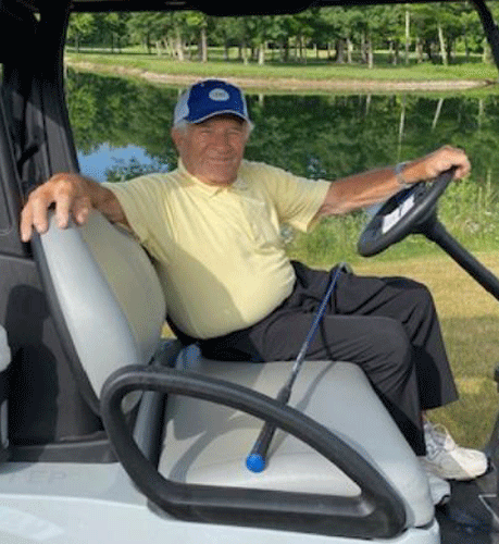 Man in golf cart near a lake.