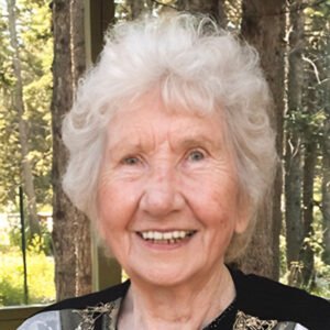 Smiling elderly woman outdoors with trees background