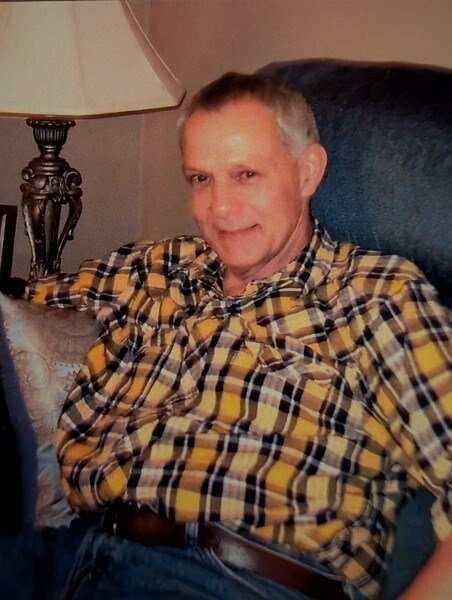 Smiling man in plaid shirt sitting on couch