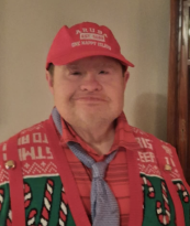 Smiling person wearing festive attire and red cap.