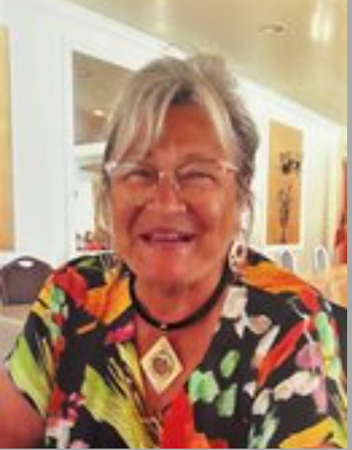 Smiling woman wearing colorful floral blouse indoors.