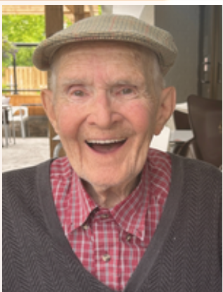 Smiling elderly man in a cap and sweater.