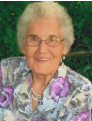 Elderly woman smiling wearing floral blouse outdoors.