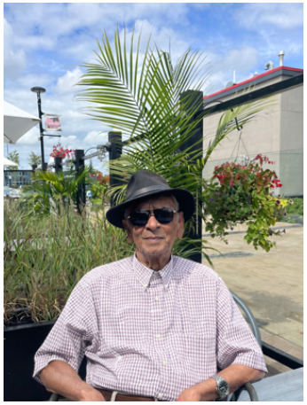 Man in hat and sunglasses outdoors.