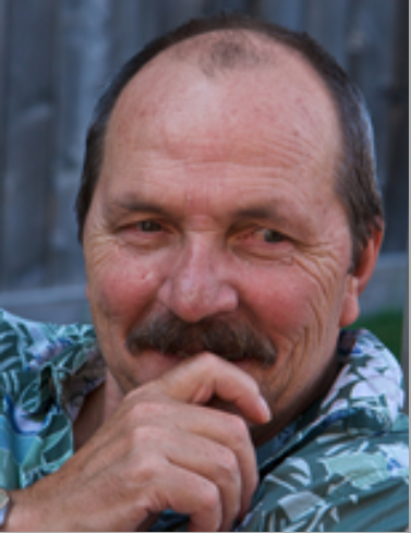 Smiling man with mustache and floral shirt.