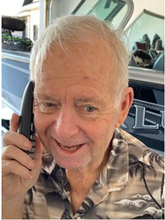 Smiling man talking on phone near a boat