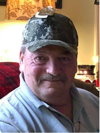 Smiling man wearing a camo cap indoors.