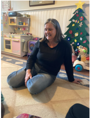 Woman sitting in playroom with toys and decorations.