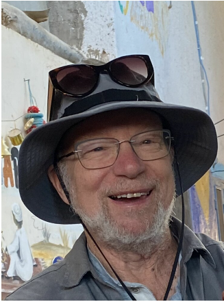 Smiling man wearing hat and sunglasses indoors.