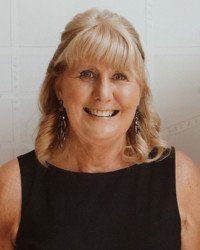 Smiling woman with blonde hair and black dress.