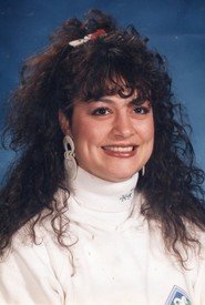 Smiling woman with curly hair and white turtleneck.
