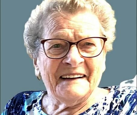 Smiling elderly woman with glasses, blue shirt