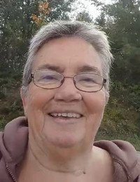Smiling person outdoors with trees behind.