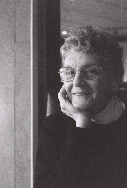 Elderly woman smiling in glasses, black and white photo.