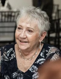 Elderly woman smiling at a formal event.