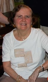 Smiling woman in white shirt seated indoors.
