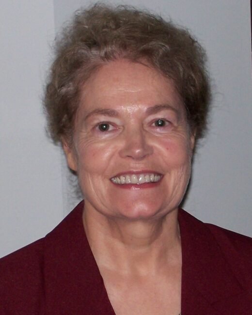 Smiling person wearing a maroon jacket indoors.