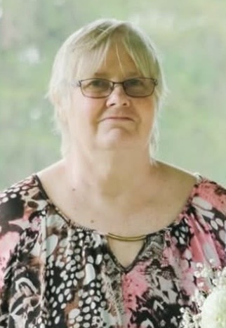 Woman in floral top with short hair and glasses.