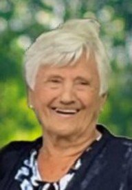 Smiling elderly woman with short white hair outdoors.