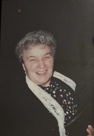 Smiling person in a patterned shirt and scarf.