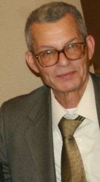 Elderly man in suit and glasses smiling