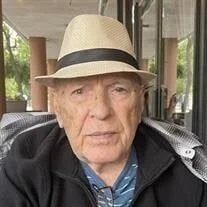 Elderly man wearing hat sitting outdoors