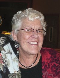Smiling elderly woman wearing glasses and earrings.