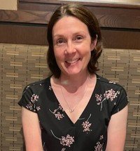 Smiling woman sitting in a restaurant booth.