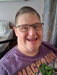 Smiling person with glasses in a purple shirt.