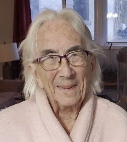 Senior woman smiling indoors wearing glasses and robe