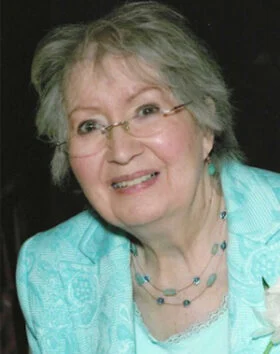 Elderly woman smiling in formal attire.