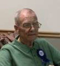 Elderly man wearing glasses and a green shirt