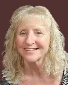 Smiling person with curly blonde hair on brown background.