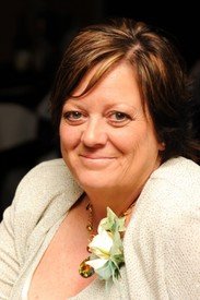 Smiling person in formal attire with flower pin