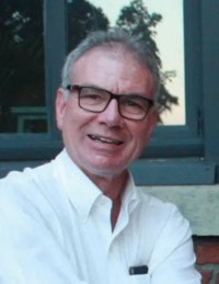 Man in glasses smiling by a window.