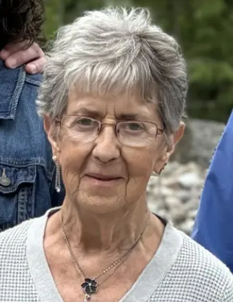 Elderly woman with short gray hair outdoors.