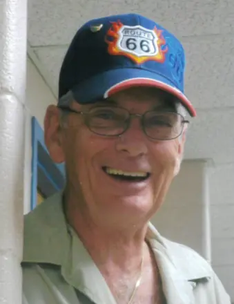 Smiling man wearing Route 66 cap indoors.