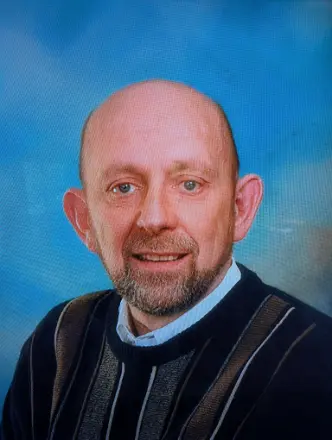Person smiling, wearing striped sweater, blue background.