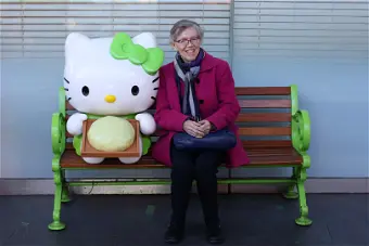 Person sitting with large Hello Kitty on bench.