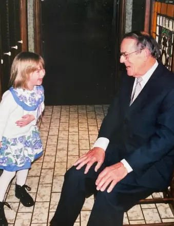 Child and elderly man smiling indoors.