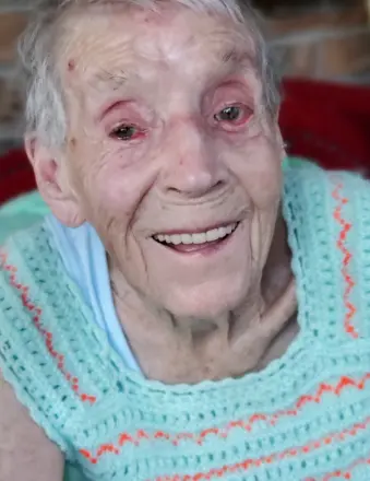 Elderly woman smiling while seated indoors