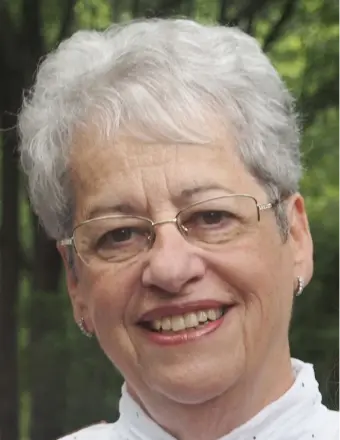 Smiling older woman with white hair and glasses.