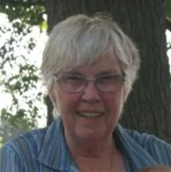 Smiling elderly woman outdoors with trees behind