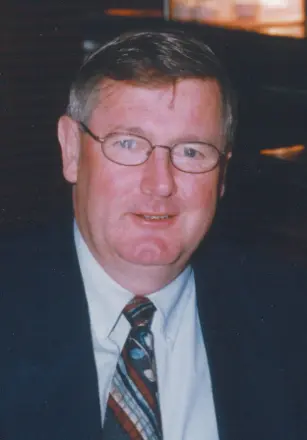 Man with glasses and tie, smiling casually.