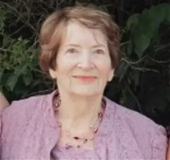 Elderly woman smiling outdoors.