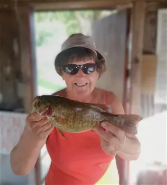 Person holding fish inside wooden cabin